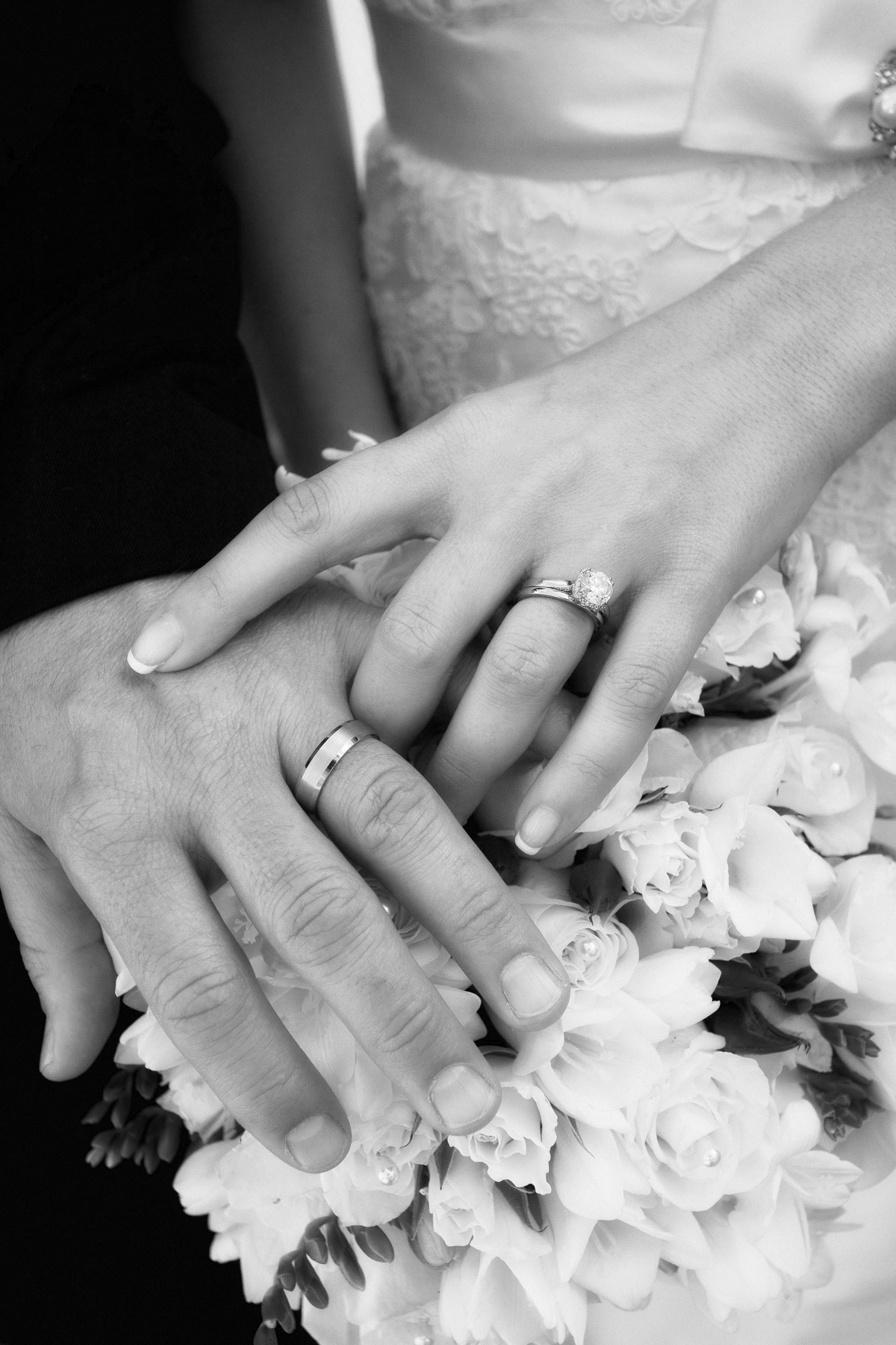 A black and white close up of flowers, hands and rings,  at the Holy Cross Greek Orthodox Church in Belmont