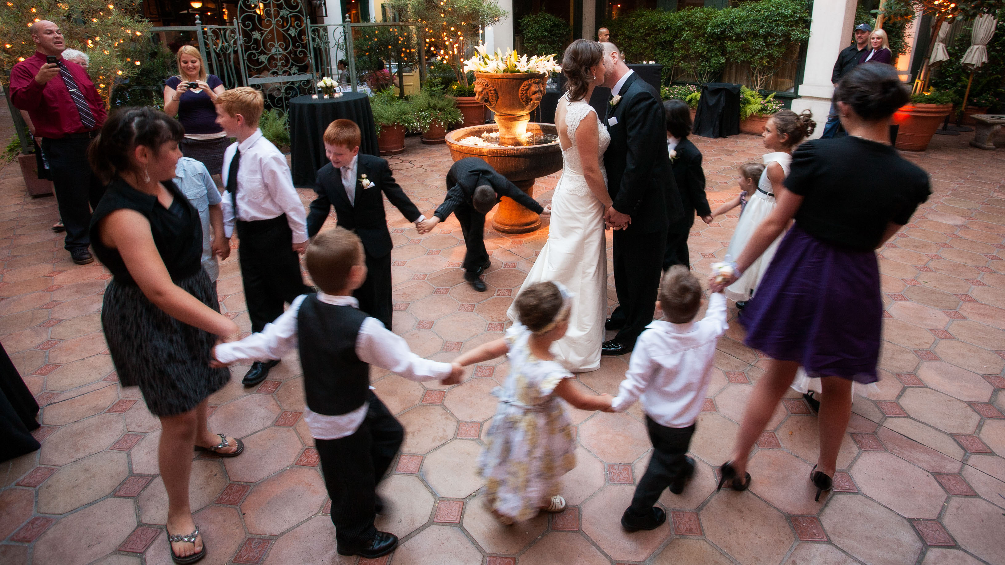 The bride and groom kiss as a circle of children dance around them,  at the Garden Court Hotel in Palo Alto