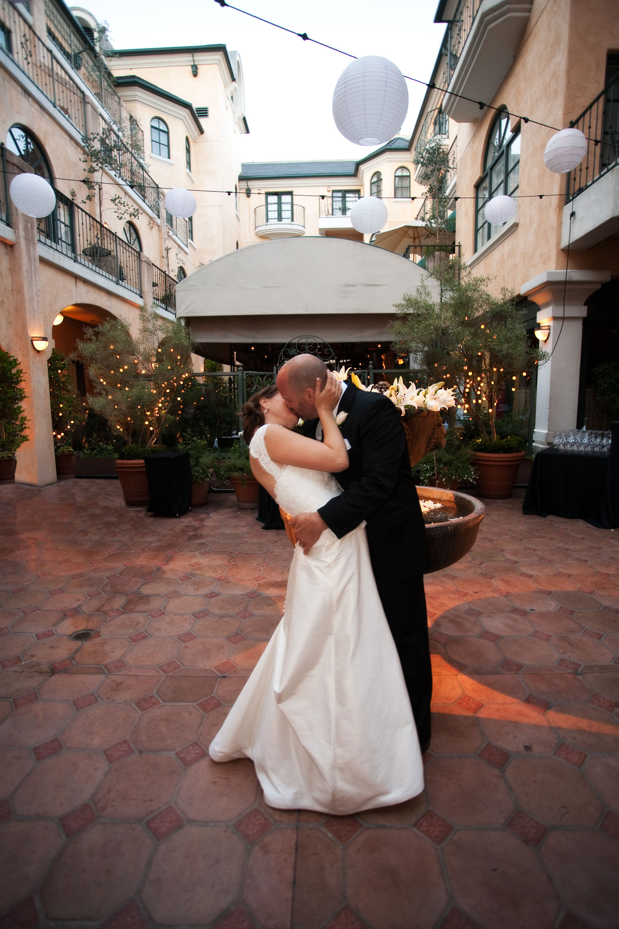 The bride and groom kiss in the courtyard  at the Garden Court Hotel in Palo Alto