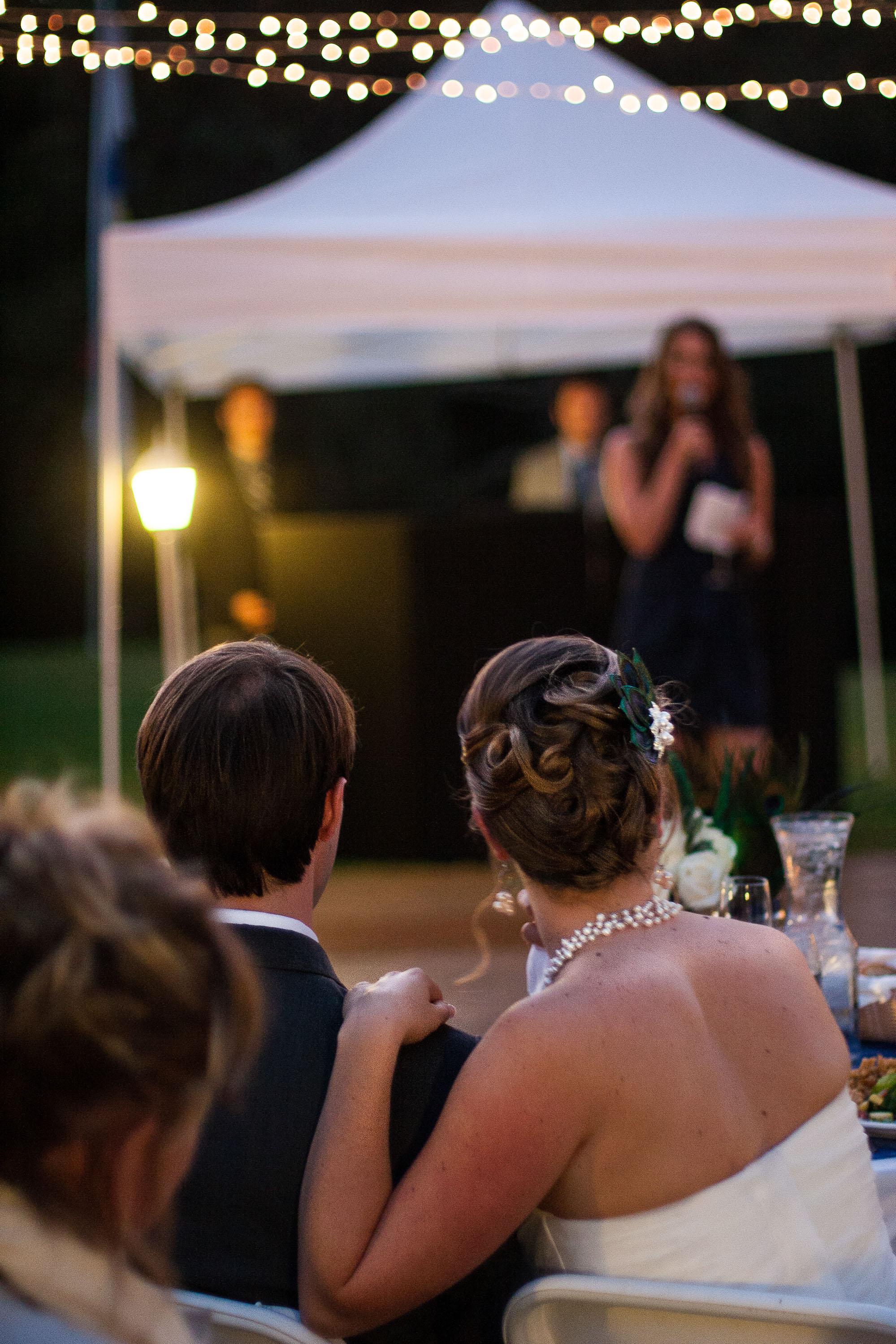 The bride and groom look on as one of their friends gives them a toast, at Pema Osel Ling in the Santa Cruz mountains