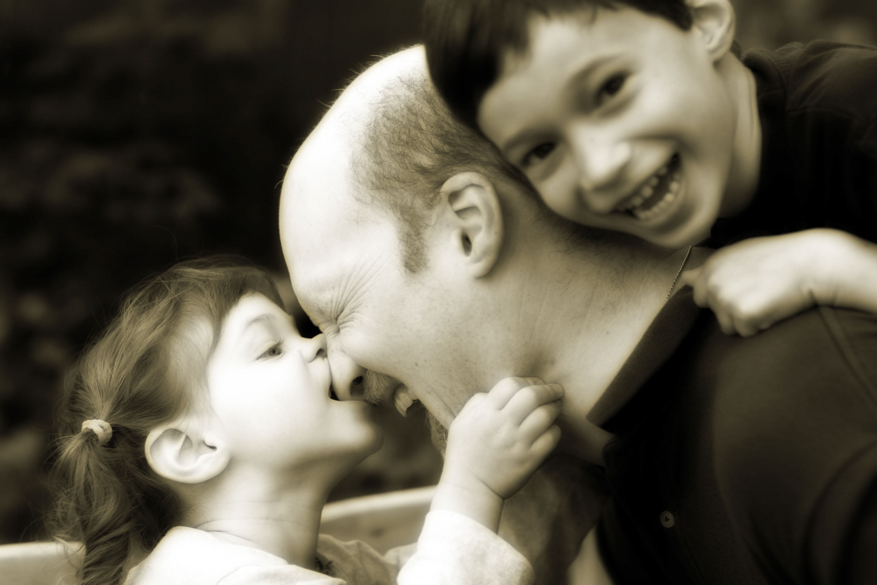 A little girl bites her daddy's nose
