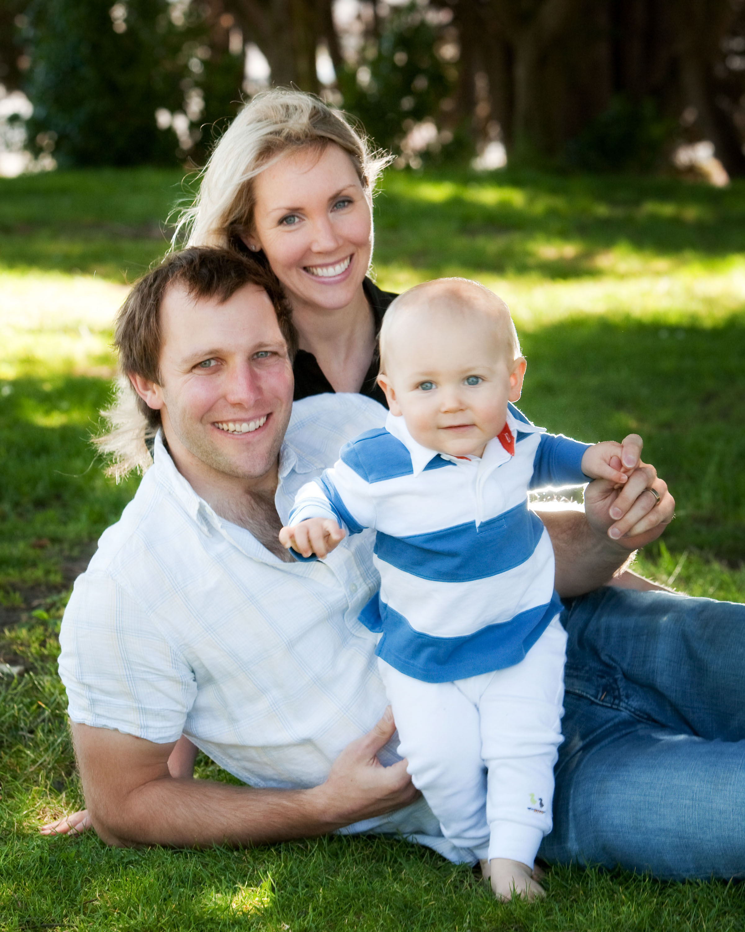 A sun-drenched family poses in a San Francisco park with their baby.