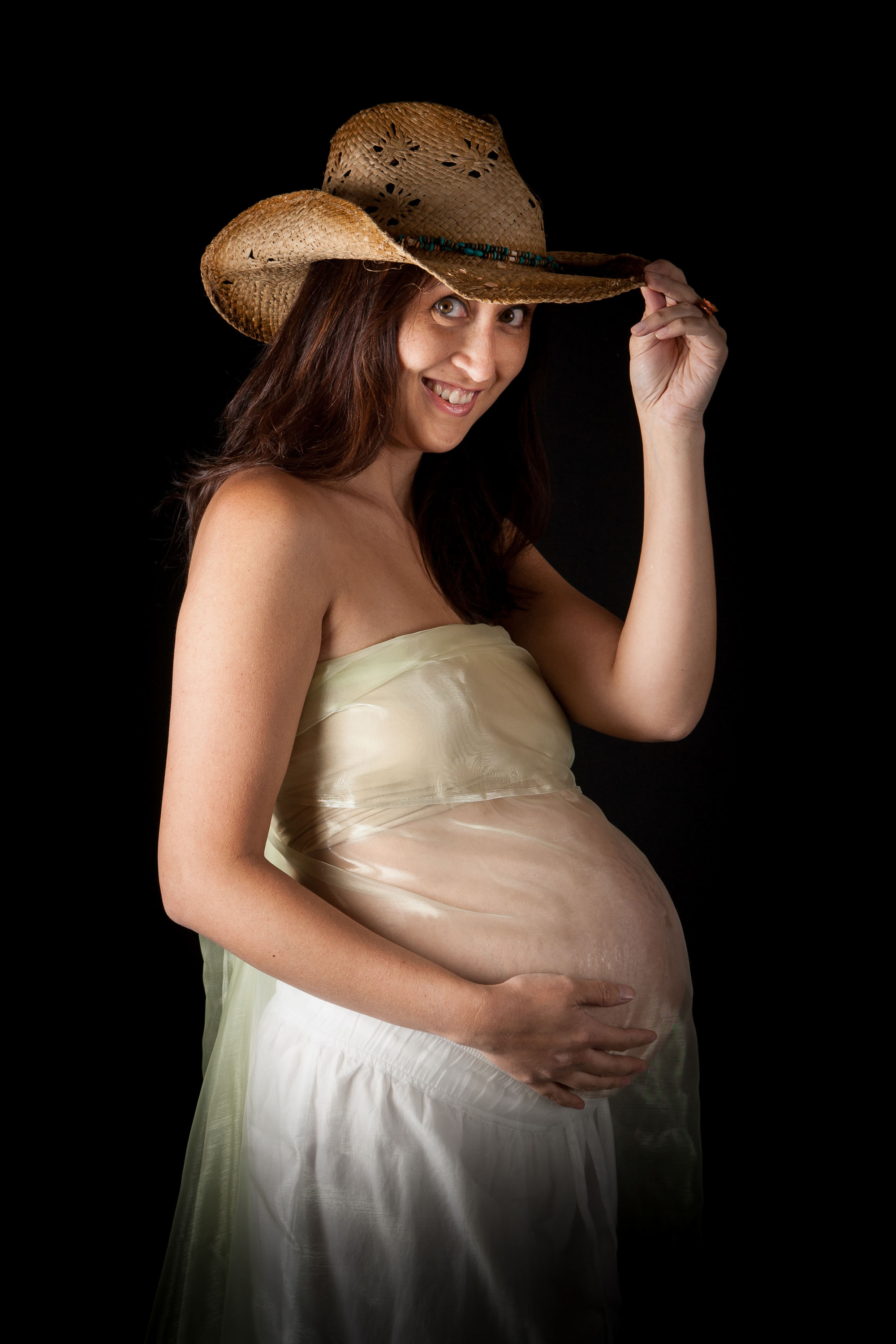 A soon-to-be mom rocks a cowboy hat for her maternity portrait, made in the Checkerbox studio.