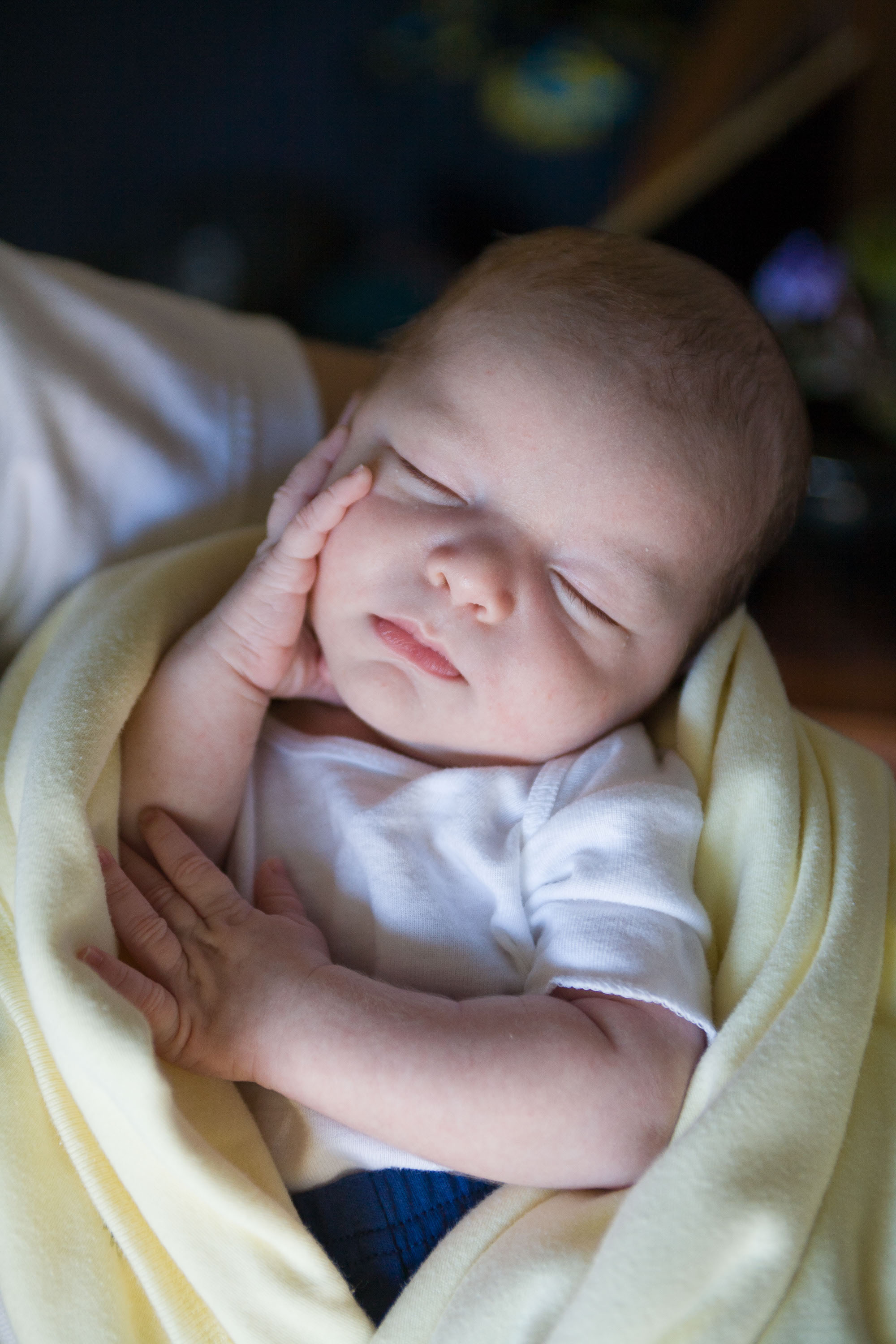 A sleeping newborn swaddled in a yellow blanket.