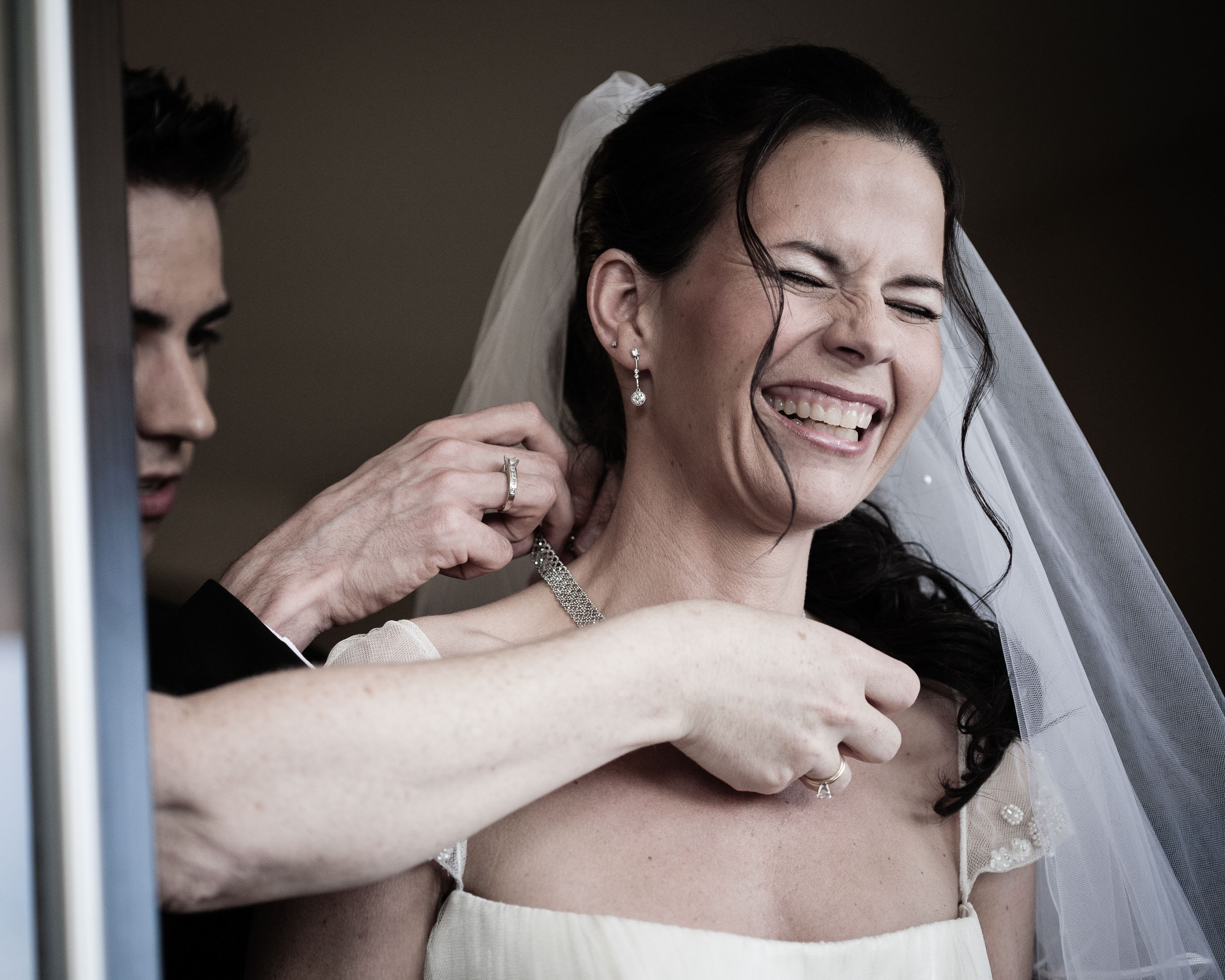 The bride laughs as her brother and mom adjust her jewelry at the St. Francis in San Francisco