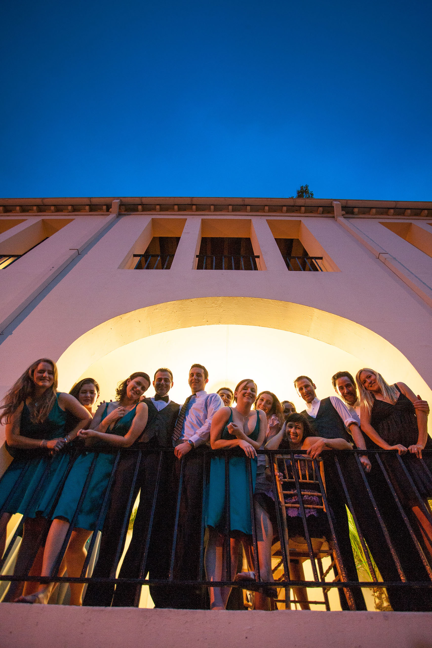 Happy wedding guests look down from the Garden Court Hotel in Palo Alto under a brilliant blue twilight