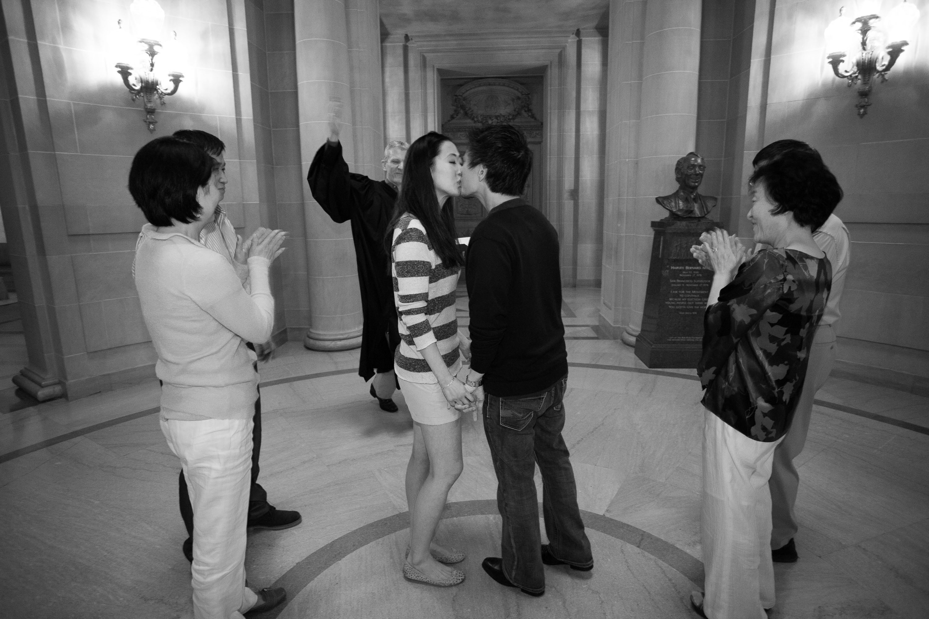 A wedding kiss, surrounded by family, at a San Francisco City Hall wedding