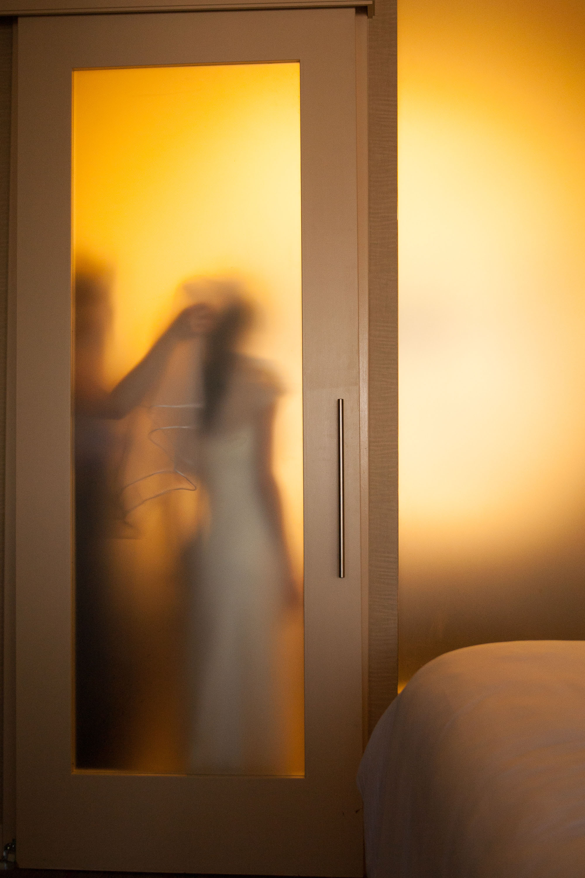 A warm and etherial image of a bride getting ready behind the frosted glass of the bridal suite at the St. Francis