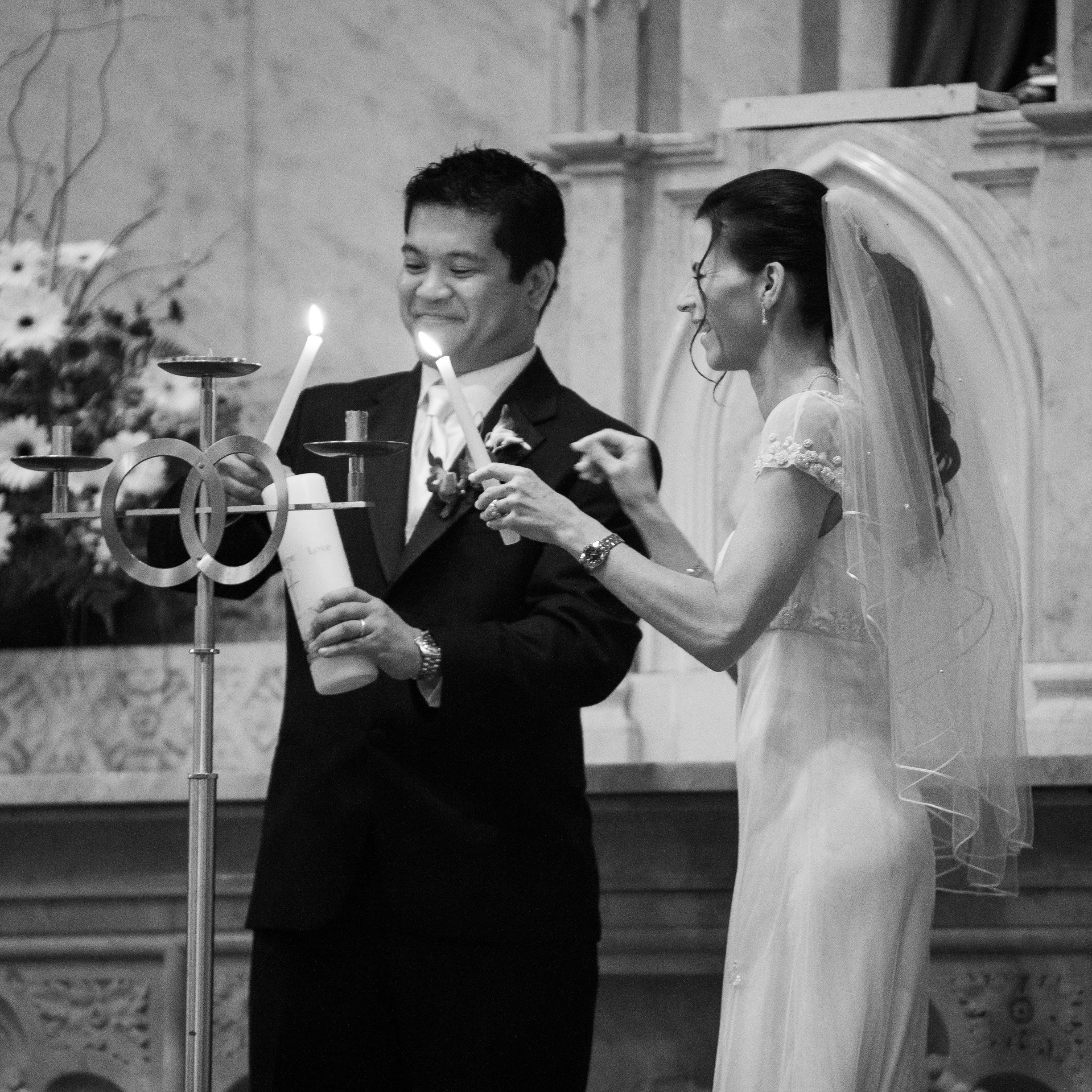 The bride and groom light one candle from two during their wedding ceremony at Old St. Mary's Church in San Francisco