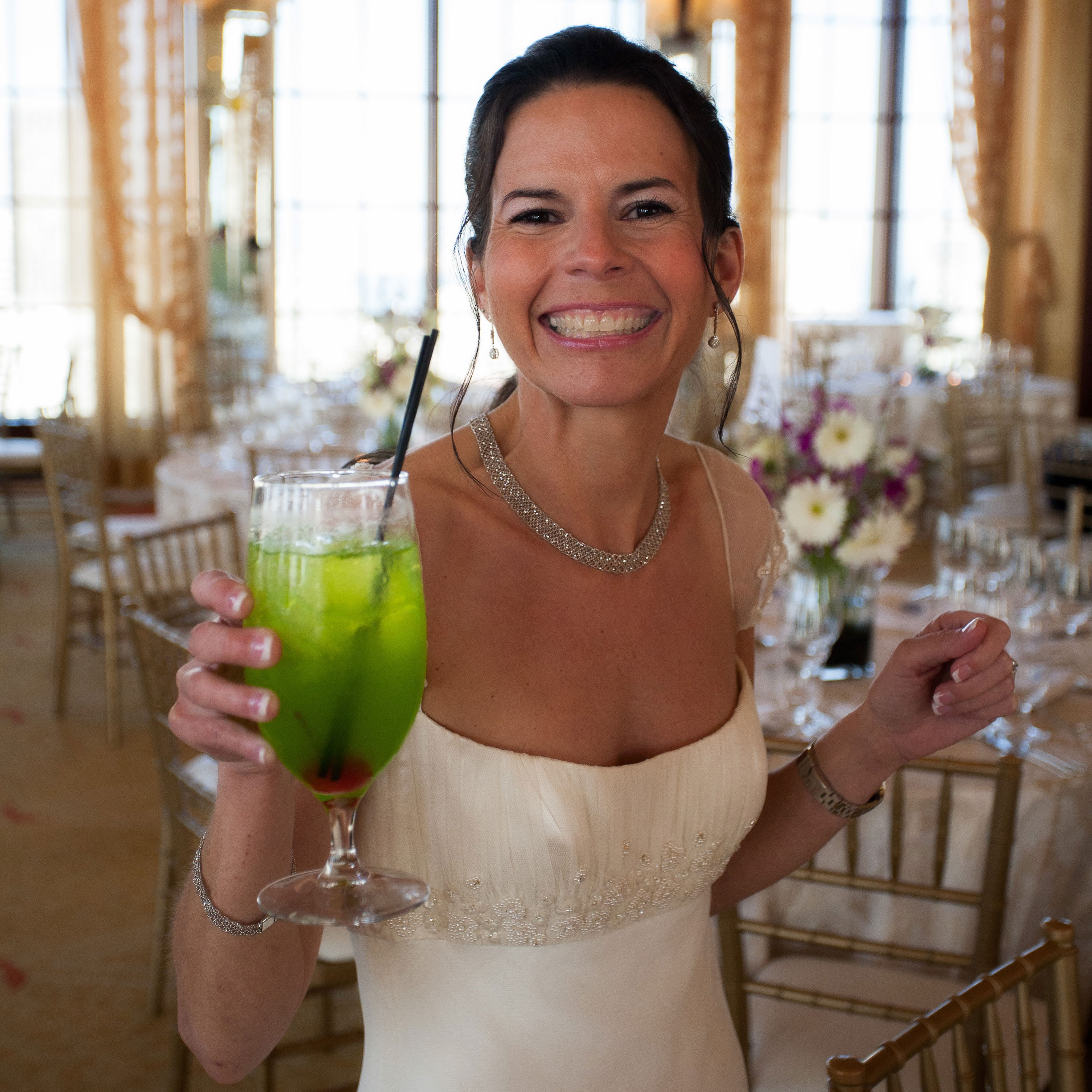 The bride grins with a bright green cocktail in her hand at the St. Francis Hotel in San Francisco