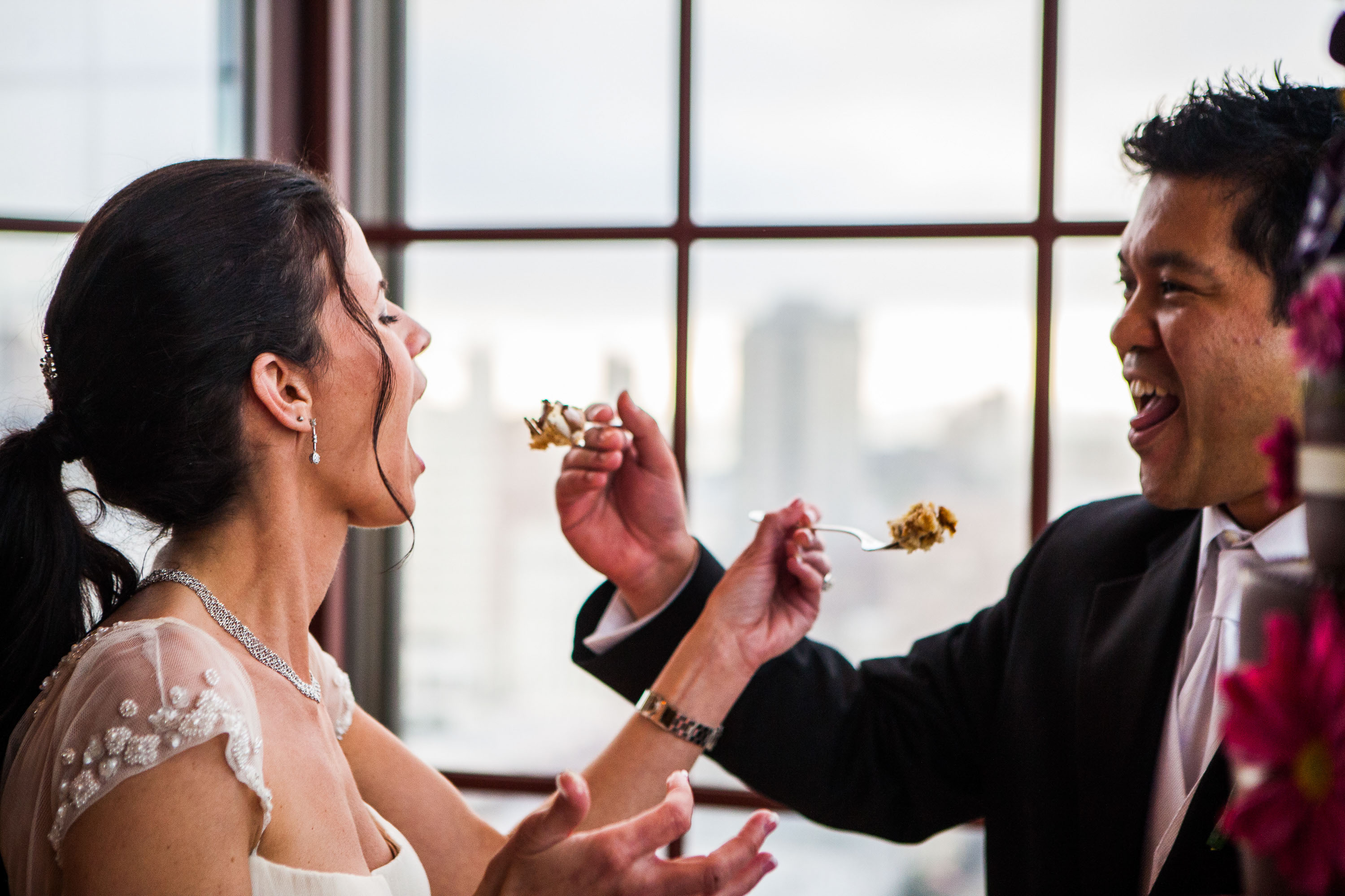 The bride and groom feed each other cake in front of the incredible view  at the St. Francis Hotel in San Francisco